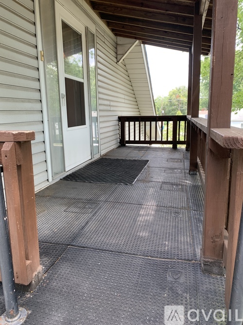 A porch with a grey floor mat and a white door.