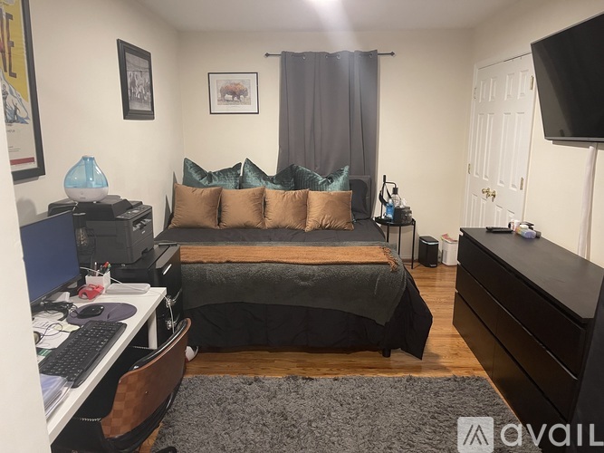 A bedroom with a bed, desk, and a television.