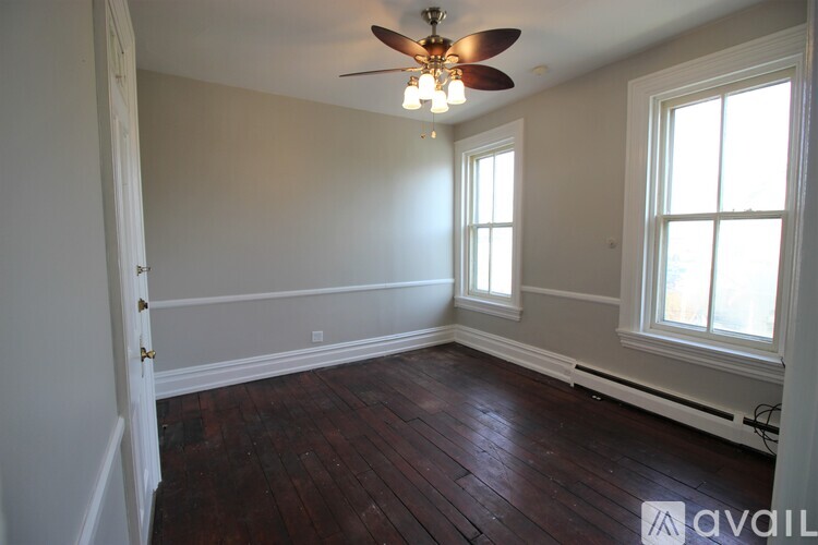 A room with a ceiling fan and wood flooring.