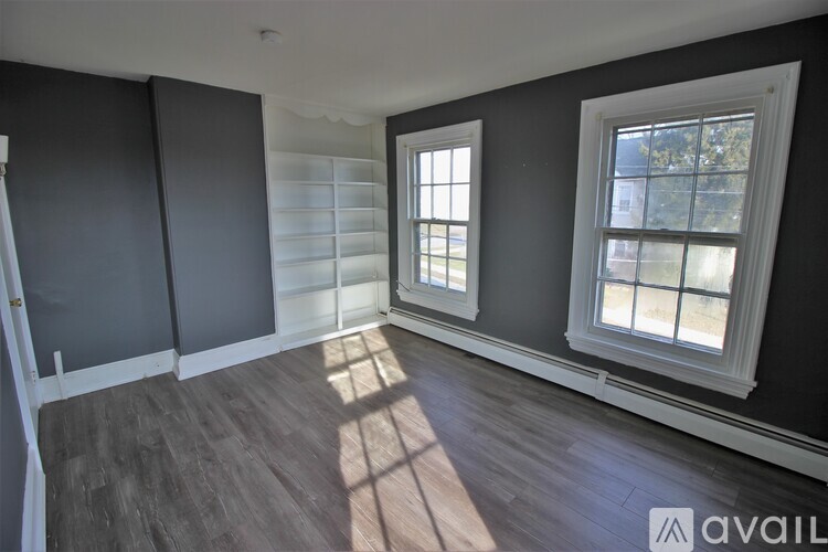 A room with a window on the right side and a wooden floor.