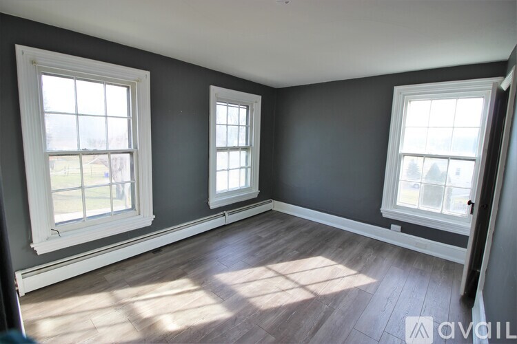 A room with three windows and wooden flooring.