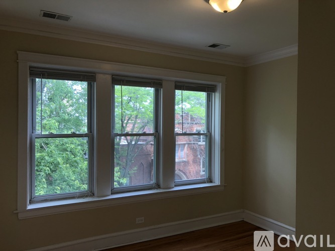 A room with a window showing a view of a tree and a building outside.
