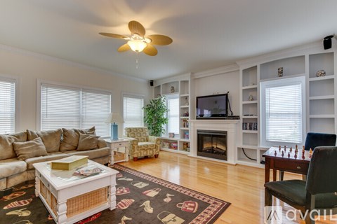A living room with a couch, a coffee table, a TV, and a ceiling fan.
