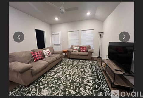 A living room with a grey couch and a black and white patterned rug.