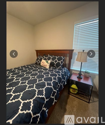 A bedroom with a bed and a nightstand with a lamp.