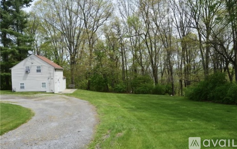 A white house with a gravel driveway in front of it.