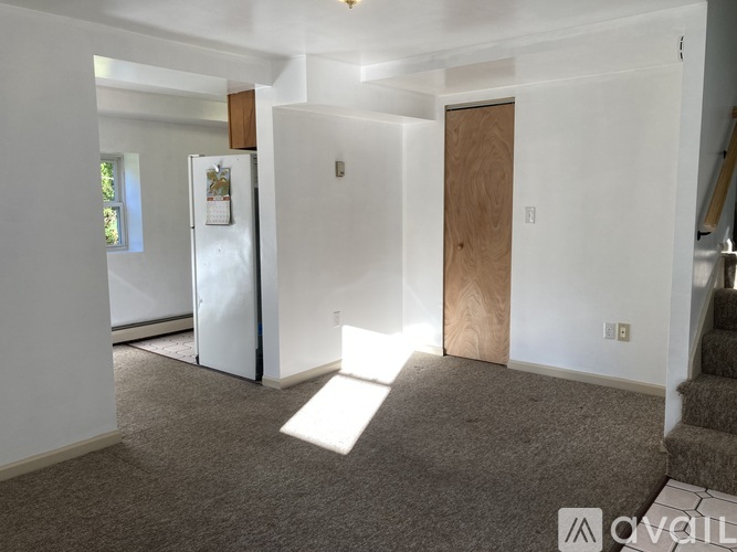 A white refrigerator is in a kitchen with a carpeted floor.