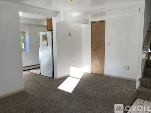 A white refrigerator is in a kitchen with a carpeted floor.