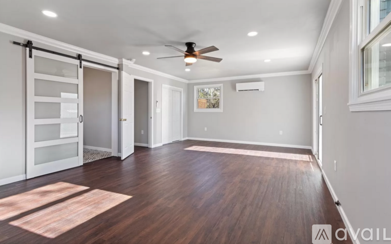 A spacious room with wooden floors and a ceiling fan.