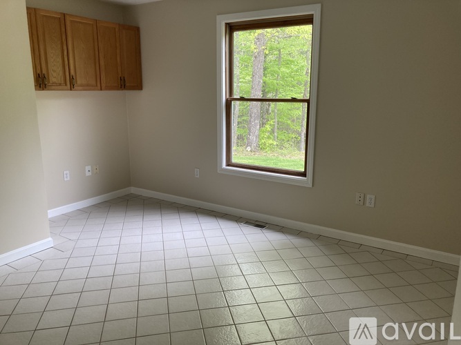 A room with a window showing trees outside.