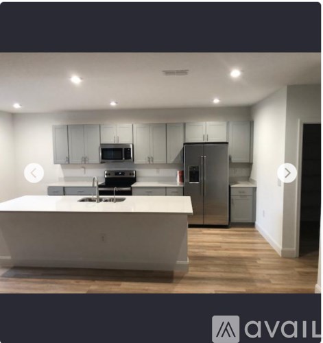 A modern kitchen with a white island and stainless steel appliances.