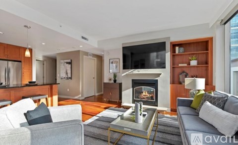 A modern living room with a grey couch and a fireplace.