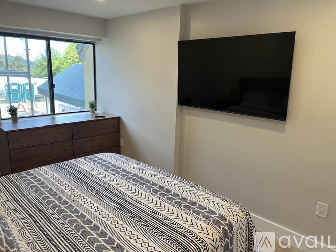 A bedroom with a large bed and a flat screen TV mounted on the wall.