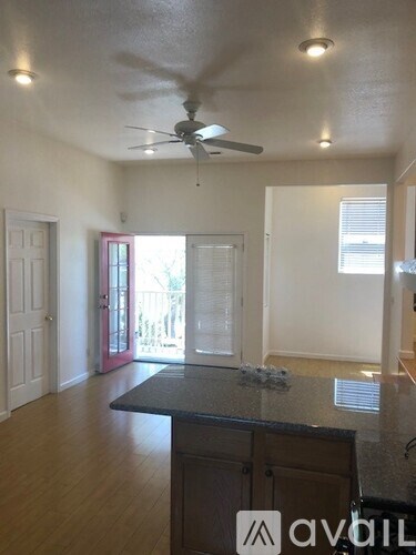 A kitchen with a black counter top and a ceiling fan.