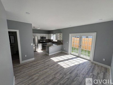 A spacious living room with a kitchen in the background.