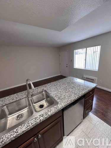A kitchen with granite countertops and stainless steel sinks.