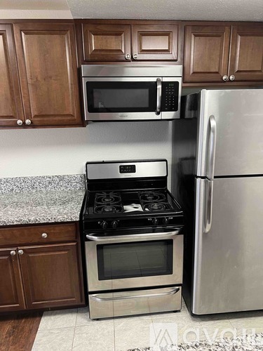 A kitchen with a stove, refrigerator, and microwave.