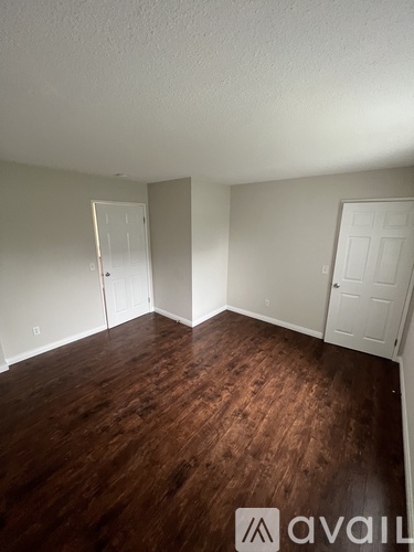 A room with wood flooring and two white doors.