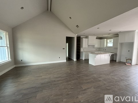 A spacious room with wooden flooring and white walls.