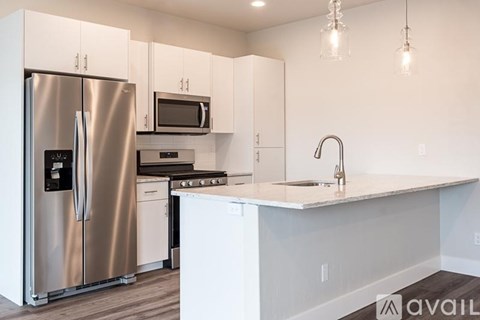 A kitchen with a stainless steel refrigerator and white cabinets.