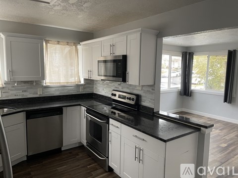 A kitchen with white cabinets and black countertops.