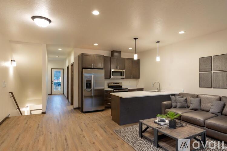 A modern kitchen and living room with wooden floors and stainless steel appliances.