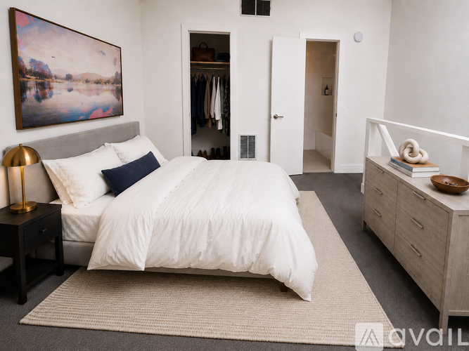 A bedroom with a large bed, a painting on the wall, and a wooden dresser.