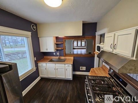 A kitchen with white cabinets and a wooden counter top.