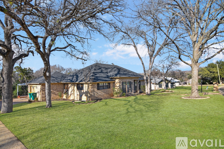 A house with a green lawn and trees in front of it.
