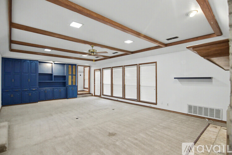 A spacious room with a ceiling fan and large windows.