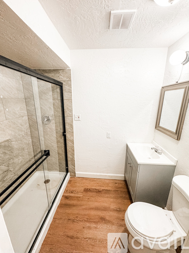 A white toilet sits in a bathroom with a glass shower door.