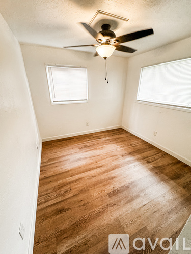 A room with a ceiling fan and wooden flooring.