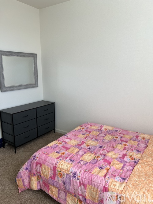 A bedroom with a bed, dresser, and mirror.