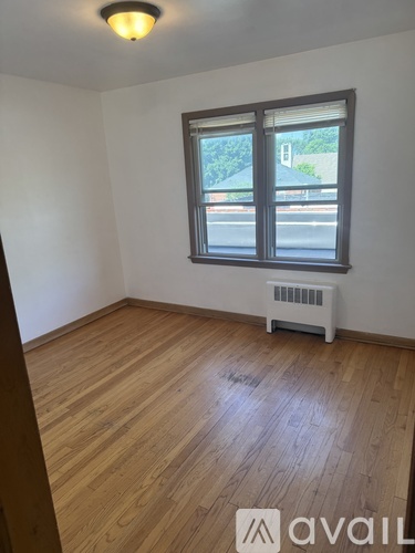 A room with wooden flooring and a window with blinds.