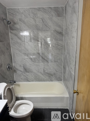 A bathroom with a toilet, tub, and wooden door.