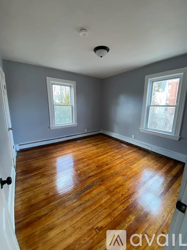 A room with wooden floors and two windows.