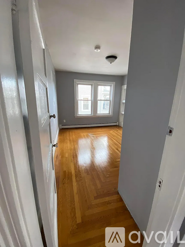 A hallway with wooden floors and white walls.