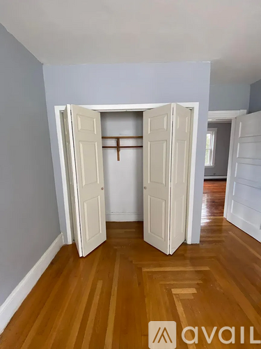 A room with a wooden floor and two open doors.