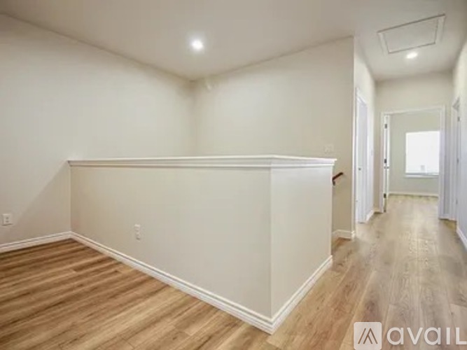 A spacious room with wooden flooring and white walls.