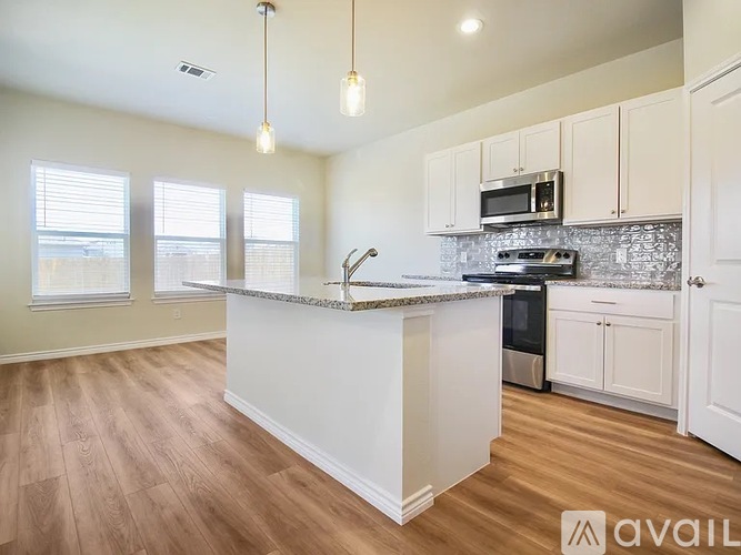 A kitchen with a white island and wooden floors.
