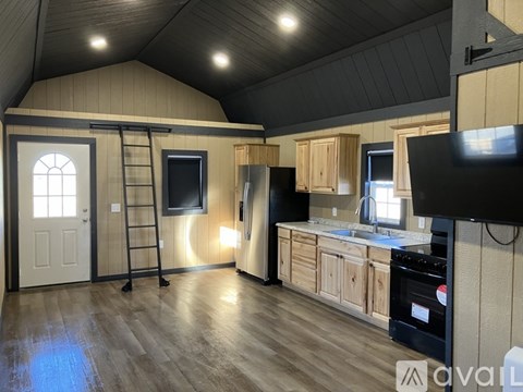 A kitchen with wooden cabinets and a black refrigerator.