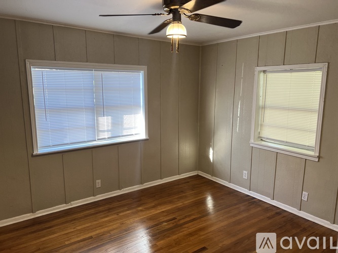 A room with wooden floors and two windows.