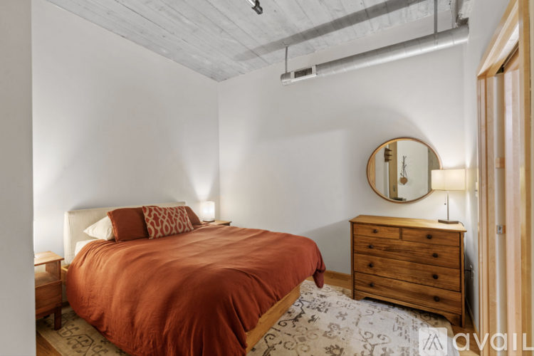A bedroom with a bed, dresser, and mirror.