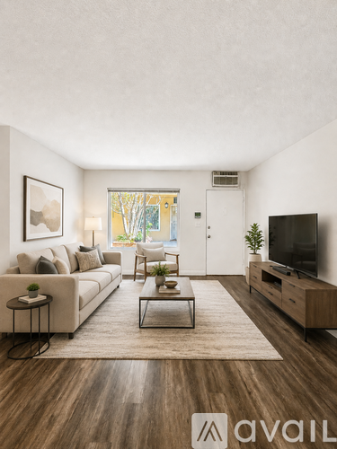 A living room with a couch, a chair, a coffee table, and a television.