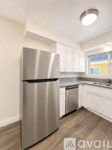 A kitchen with a stainless steel refrigerator and wooden flooring.
