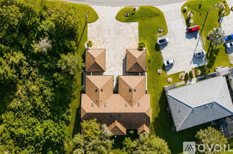 A bird's eye view of a house surrounded by trees and a parking lot.