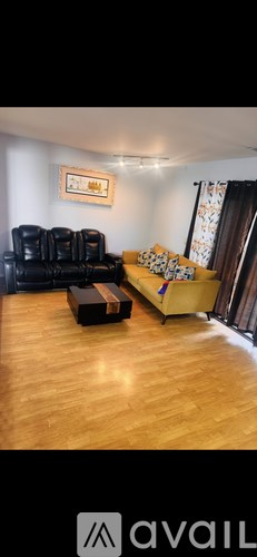 A living room with a black leather couch and a yellow sofa.
