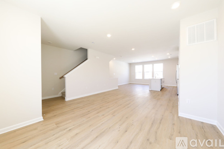 A spacious room with wooden flooring and a staircase.