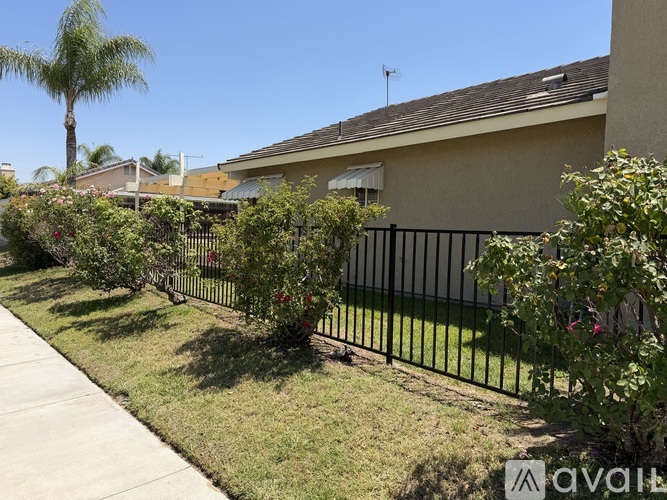 A house with a black fence and green plants in front.