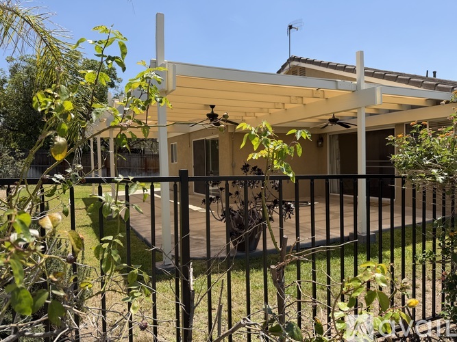 A house with a black fence and a tree in front.